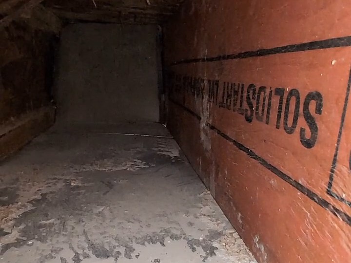 A duct run beside a roof beam, its floor covered in dust, before cleaning