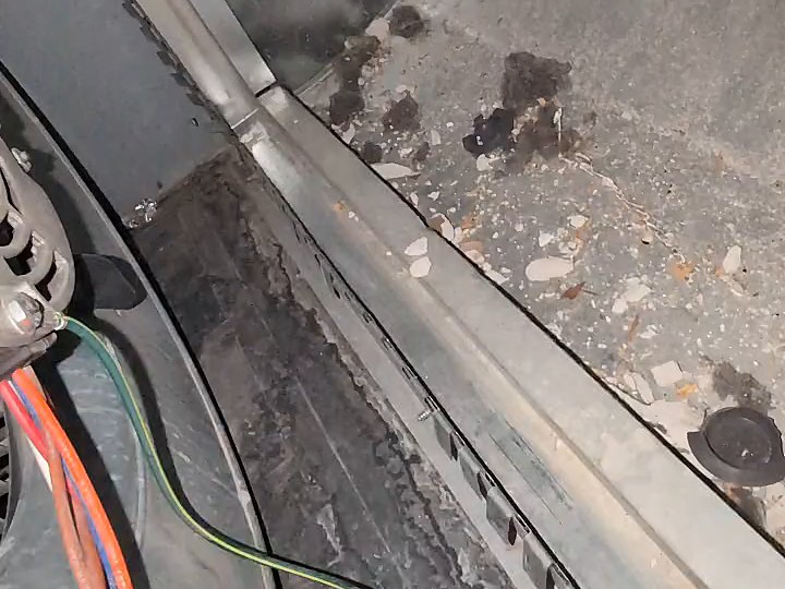 Debris and grit sitting on the shelf beside a furnace blower before cleaning