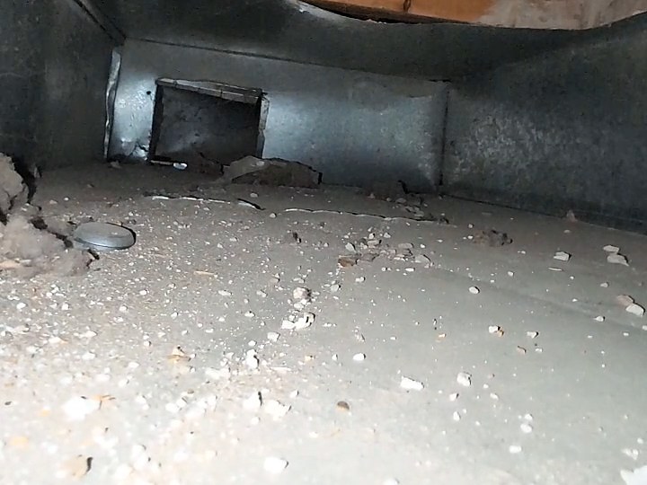 A duct floor covered in dust and chunks of drywall debris before cleaning