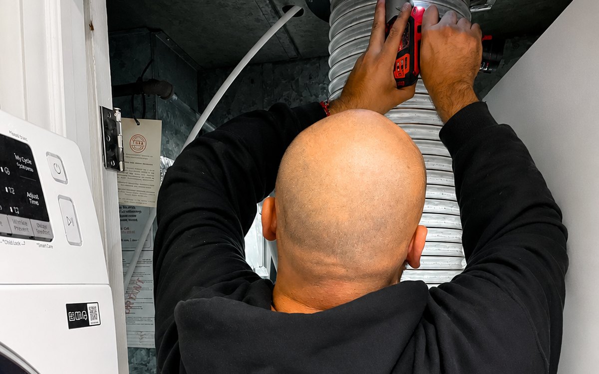 Jon working on a dryer vent line above a laundry stack